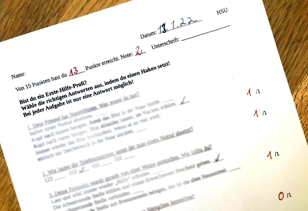 Scan eines korrigierten Multiple-Choice-Testblatts „Erste Hilfe“ im Fach HSU einer Grundschule vom 13.1.22 mit 13 von 15 Punkten und Note 2, gewertet als mündliche Note.