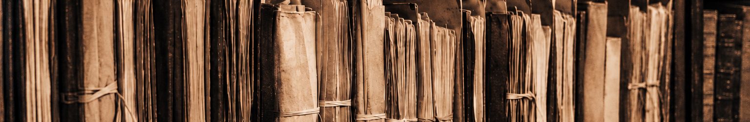 Holzregale voller alter, mit Bändern verschnürter Aktenbündel in einem Archiv