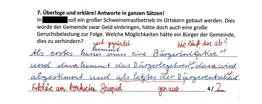 Ausschnitt aus einer Probe: Aufgabe zur Bürgerbeteiligung gegen einen geplanten Schweinemastbetrieb. Die Antwort des Kindes ist blau geschrieben und nennt Bürgerinitiative, Bürgerbegehren und Bürgerentscheid; die Korrektur der Lehrkraft ist rot, Ergebnis 2 von 4 Punkten.