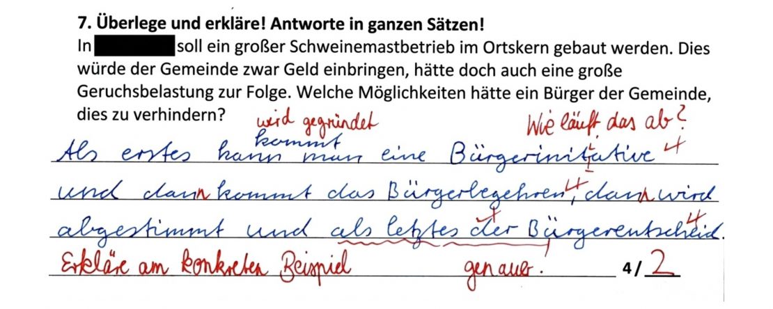 Ausschnitt aus einer Probe: Aufgabe zur Bürgerbeteiligung gegen einen geplanten Schweinemastbetrieb. Die Antwort des Kindes ist blau geschrieben und nennt Bürgerinitiative, Bürgerbegehren und Bürgerentscheid; die Korrektur der Lehrkraft ist rot, Ergebnis 2 von 4 Punkten.